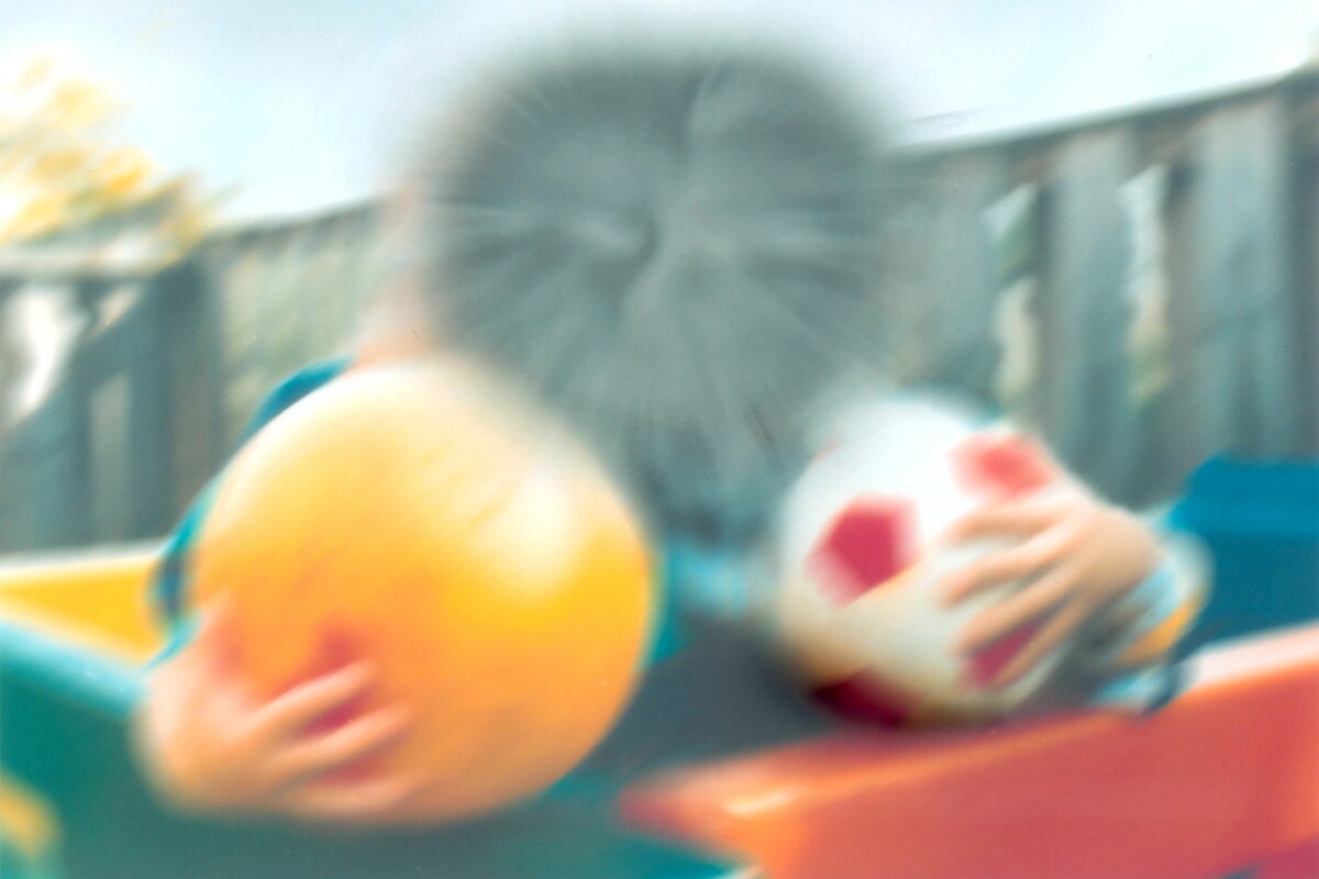 Two children with a ball, as the scene might look to a person with age-related macular degeneration: the center of the image is blurred and dark
